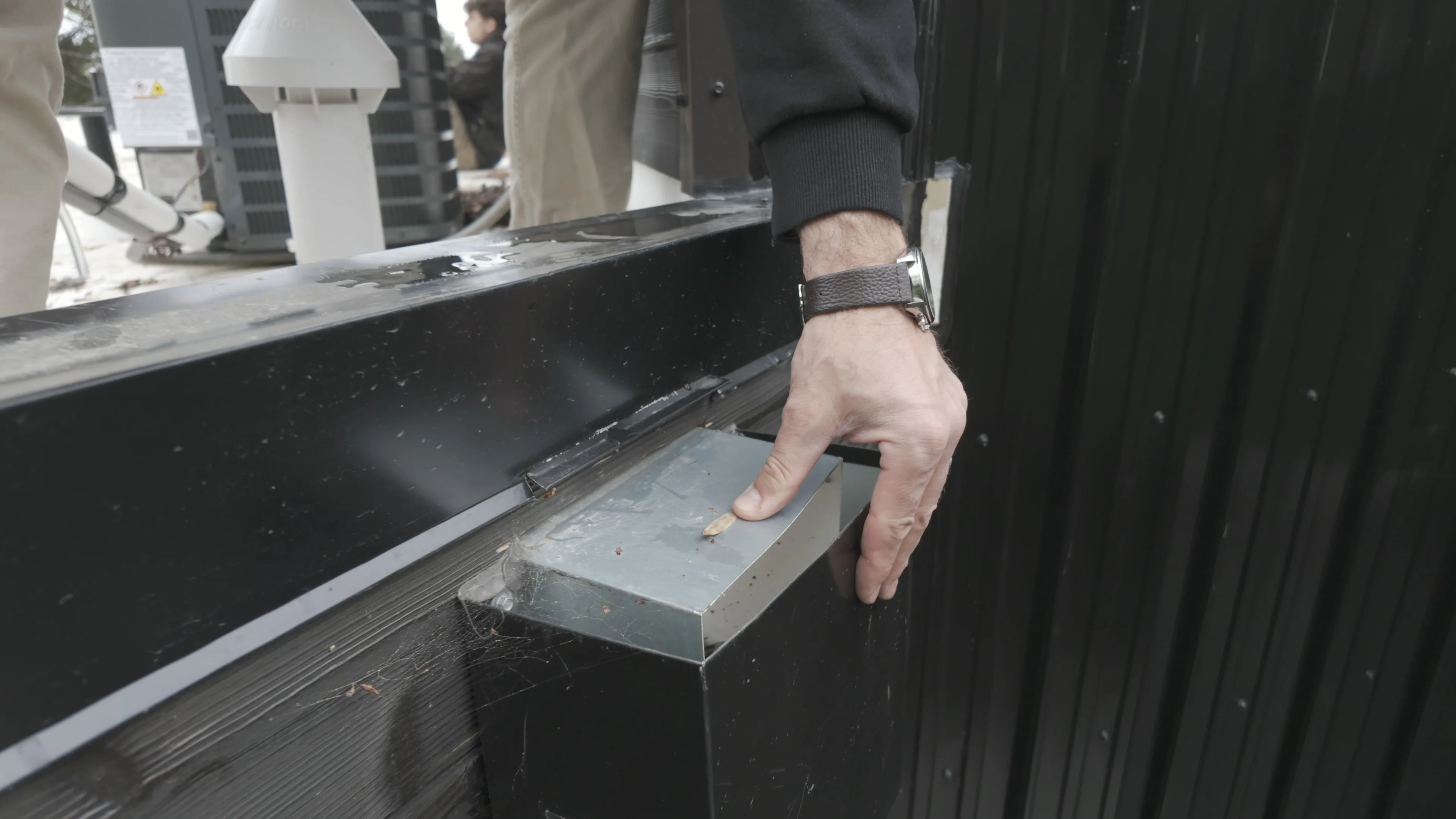 Commercial roof specialist assessing a metal edge and drainage transition