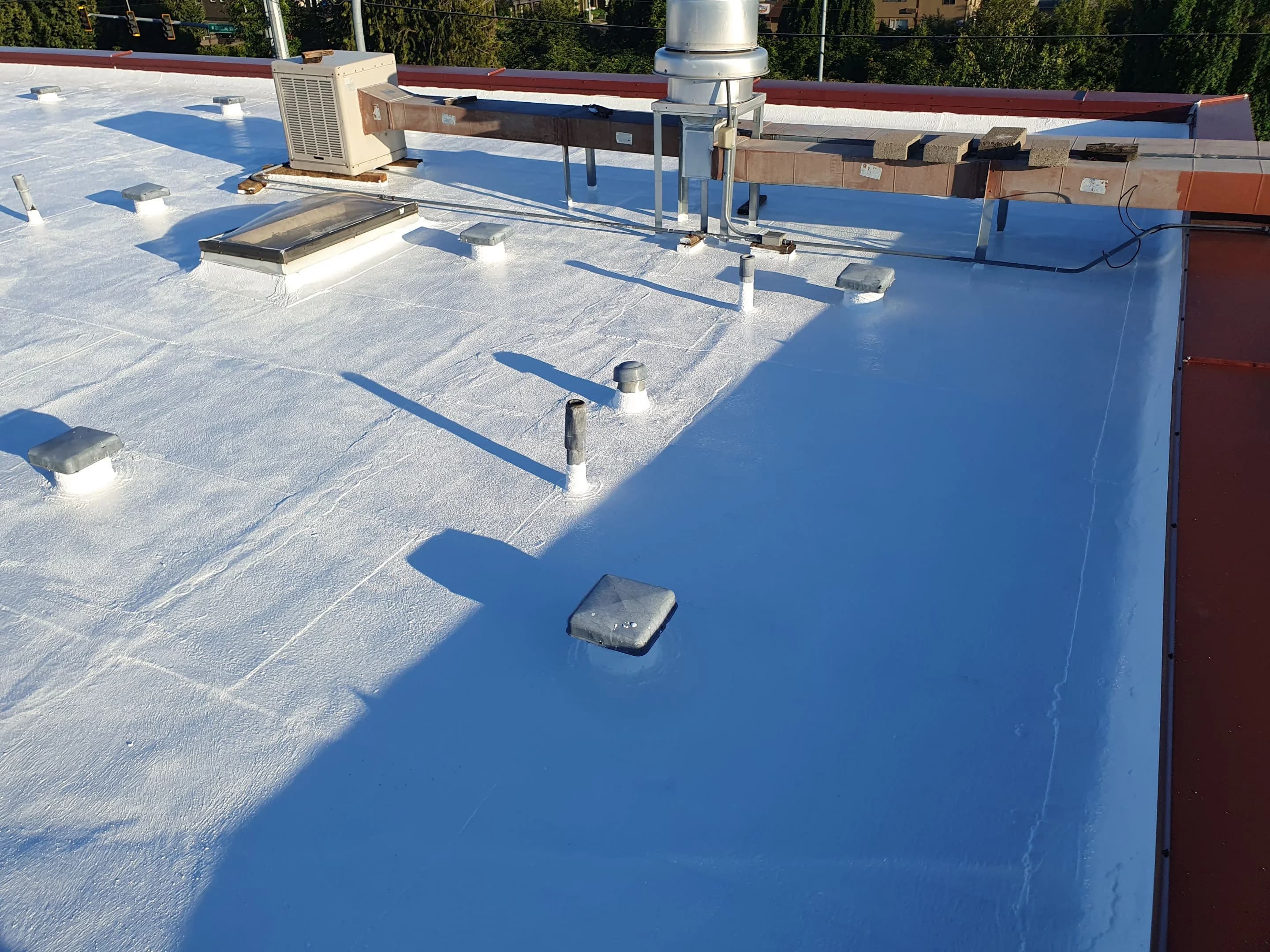Restored commercial low-slope roof around mechanical equipment, skylights, vents, and penetrations